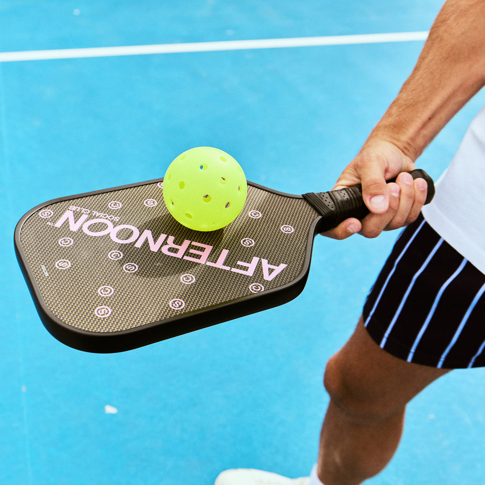 Man holding Titan Carbon Afternoon Social Club pickleball paddle and yellow rotation ball