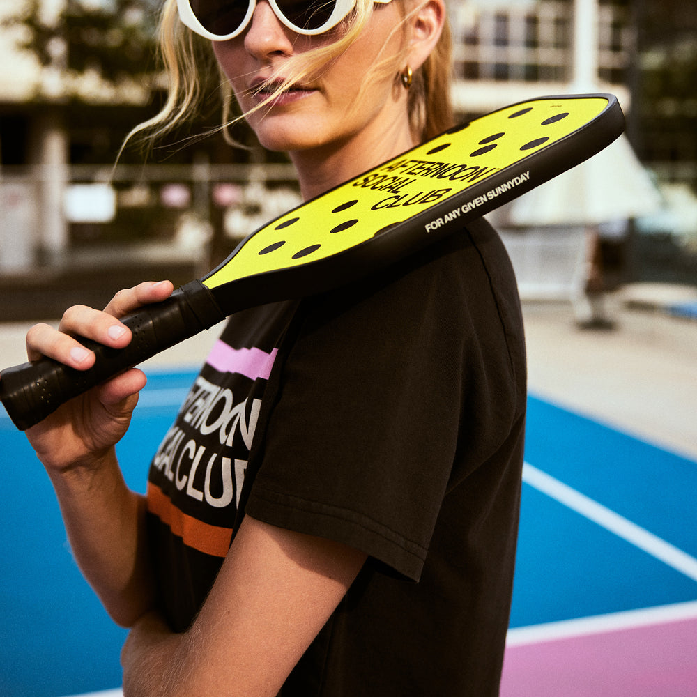 Female model holding yellow carbon fiber pickleball paddle featuring the side that says for any given sunnyday 