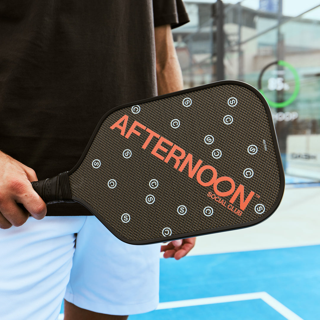 male holding black titan carbon pickleball paddle featuring the words Afternoon SC in orange and white 