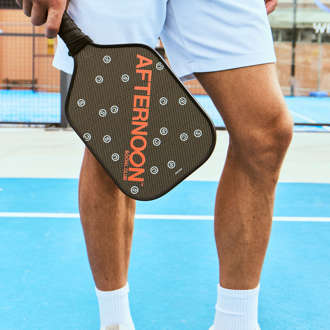 male holding black titan carbon pickleball paddle featuring the words Afternoon SC in orange and white 