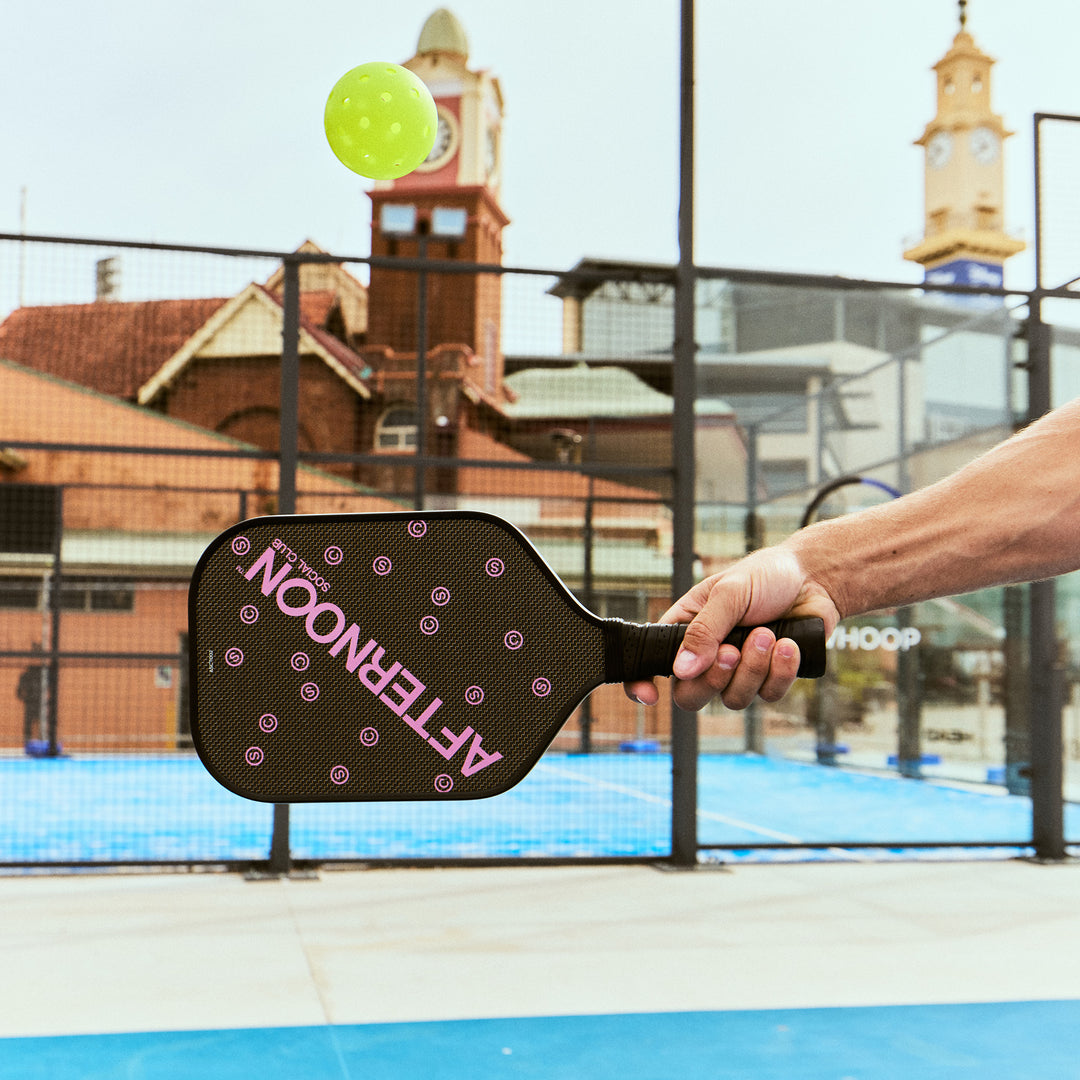 A male holding a black titan carbon pickleball paddle with the words Afternoon SC in purple