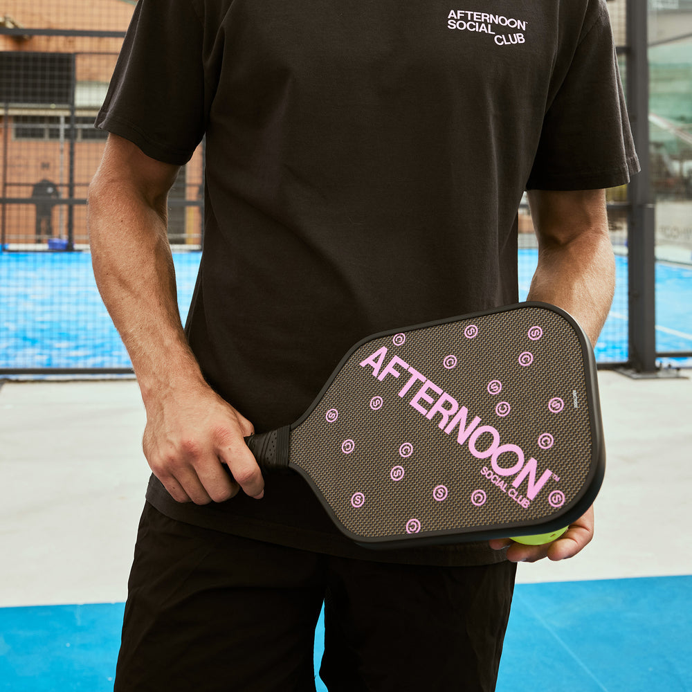 A male holding a black titan carbon pickleball paddle with the words Afternoon SC in purple